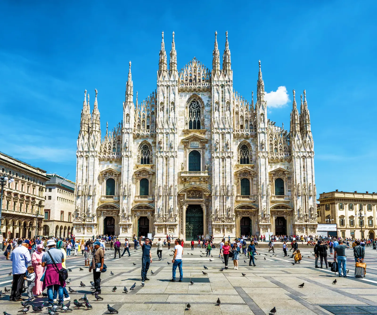 Nhà thờ Duomo Milan với nhiều tháp nhọn trắng và du khách trên quảng trường