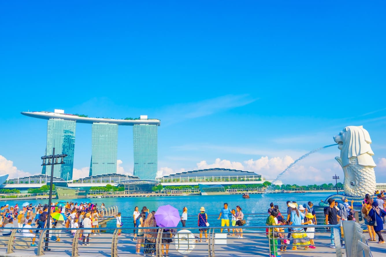 Tượng Merlion phun nước với tòa nhà Marina Bay Sands ở phía sau. Dòng người du lịch dưới bầu trời xanh trong vắt càng làm tăng thêm sức sống cho đường chân trời Singapore.