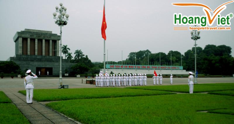 Đội nghi lễ mặc quân phục trắng đứng trên quảng trường, lá cờ đỏ và Lăng Chủ tịch Hồ Chí Minh phía sau