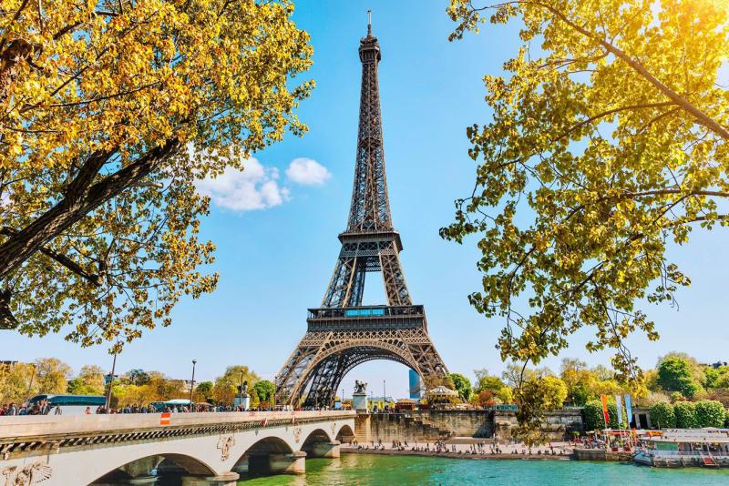 Tháp Eiffel nhìn qua tán lá vàng bên cây cầu và dòng sông Seine ở Paris