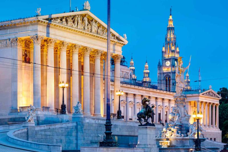 Tòa nhà Quốc hội Áo với hàng cột Hy Lạp và tháp Tòa thị chính Vienna lên đèn lúc chạng vạng