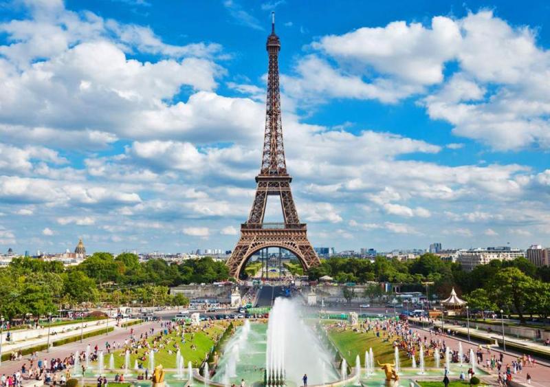 Tháp Eiffel nhìn từ vườn Trocadéro với đài phun nước và du khách đang nghỉ ngơi trên bãi cỏ