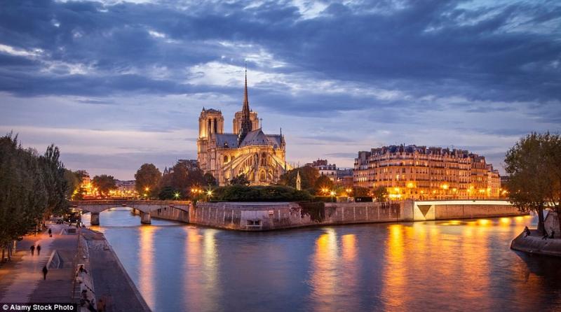 Nhà thờ Đức Bà Paris bên sông Seine lúc chiều tối, ánh đèn vàng phản chiếu trên mặt nước