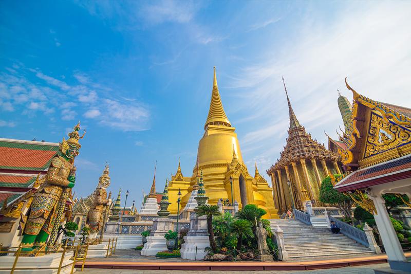 Tháp vàng, tượng thần giữ chùa và bậc thang dẫn vào đền dưới bầu trời xanh