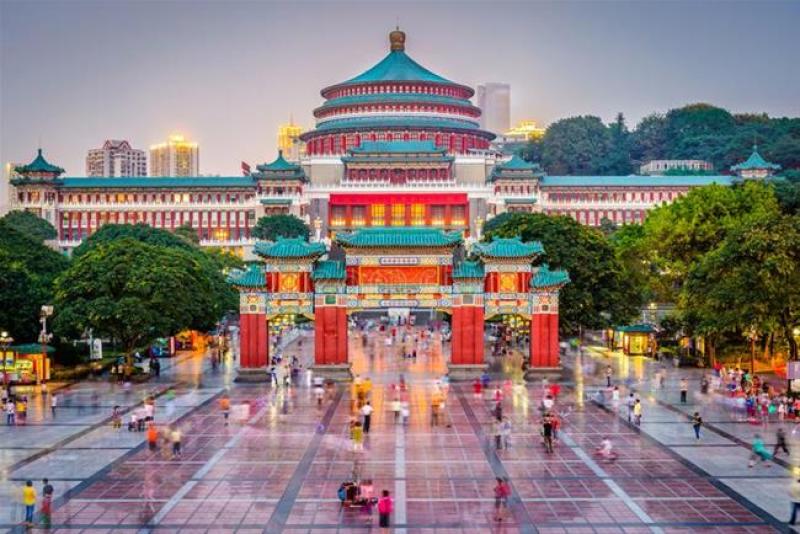 Hội trường Nhân dân mái xanh và cổng chào đỏ cùng quảng trường đông người lúc chiều tối
