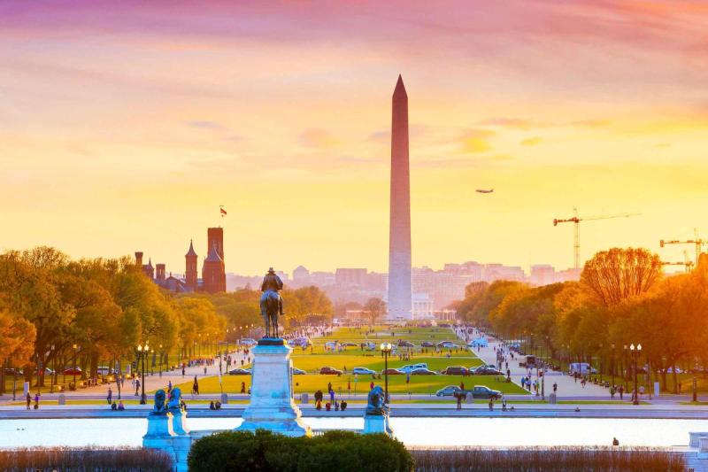 Đài tưởng niệm Washington vào mùa thu lúc hoàng hôn với hàng cây lá vàng cam và bầu trời rực sắc hồng vàng.