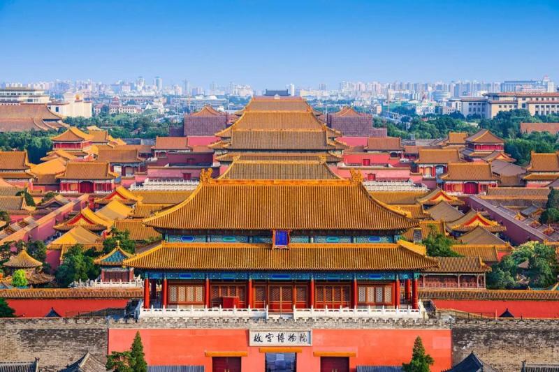 Hình ảnh từ trên cao của Tử Cấm Thành ở Bắc Kinh, cho thấy những mái nhà màu đỏ và vàng được trang trí công phu. Quần thể kiến trúc rộng lớn này nổi bật trên nền trời xanh trong vắt và khung cảnh thành phố phía sau.
