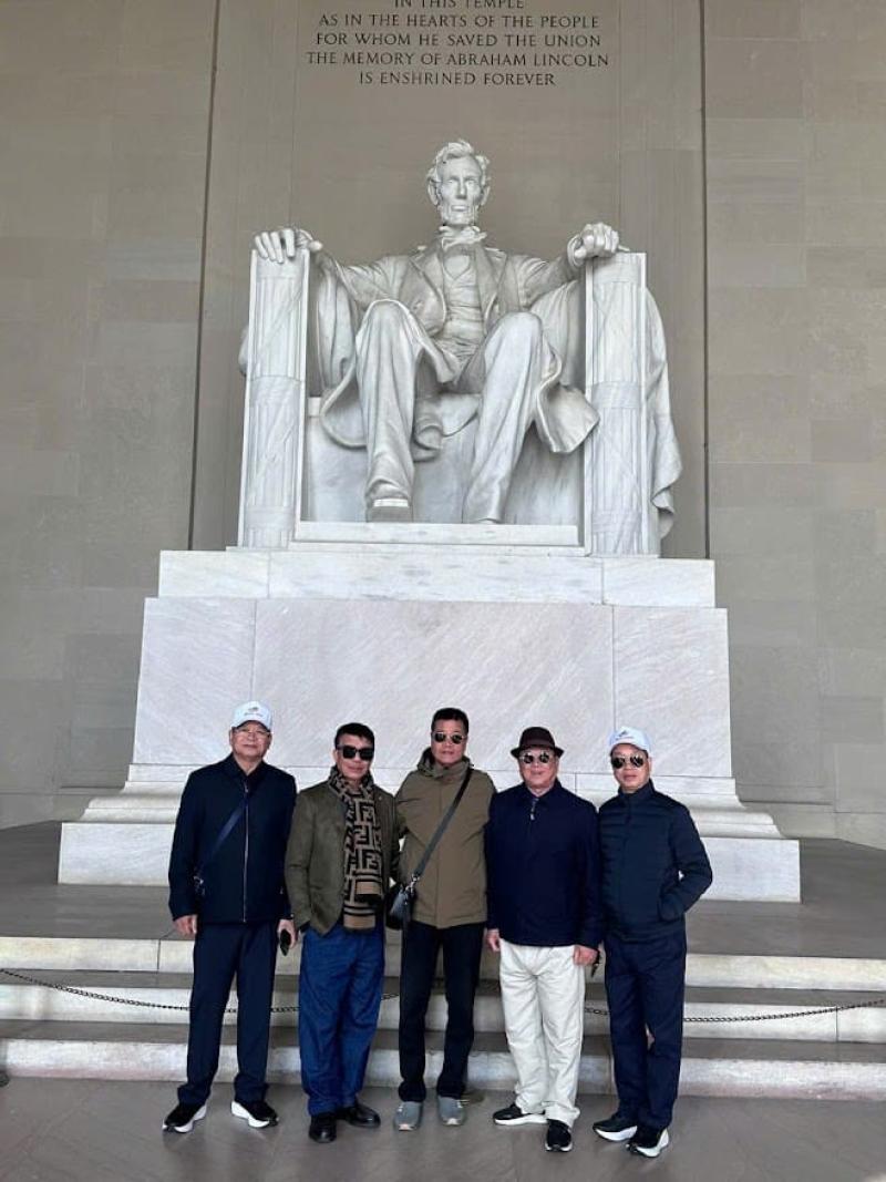 Năm người đứng mỉm cười trước bức tượng lớn của Abraham Lincoln tại Đài tưởng niệm Lincoln. Khung cảnh trang trọng và đầy vẻ tôn kính.