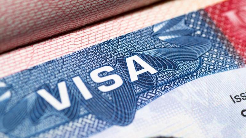 Ảnh cận cảnh thị thực Hoa Kỳ với chữ "VISA" được in đậm màu trắng nổi bật trên nền xanh có họa tiết, tạo cảm giác đây là một tài liệu chính thức.