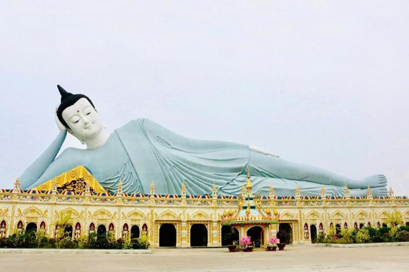 Tượng Phật nằm khổng lồ màu xanh nhạt phía trên dãy kiến trúc vàng trong khuôn viên chùa