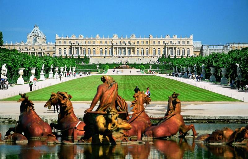 Cung điện Versailles nhìn qua thảm cỏ và đài phun nước tượng ngựa đồng