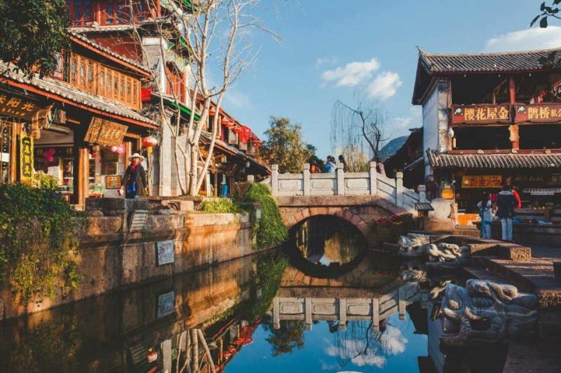Cây cầu đá nhỏ bắc qua dòng nước trong phố cổ Lệ Giang, hai bên là nhà gỗ truyền thống