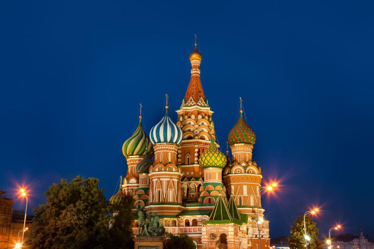 Nhà thờ Thánh Basil ở Moscow được chiếu sáng vào ban đêm, với những mái vòm hình củ hành đầy màu sắc nổi bật trên nền trời xanh thẳm, tạo nên một khung cảnh sống động và tráng lệ.