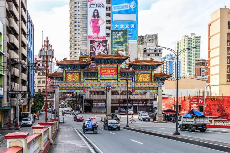 Cổng chào phố người Hoa kiểu truyền thống bắc ngang con đường đông đúc ở Manila.