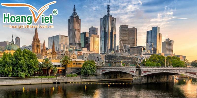 Các tòa nhà chọc trời Melbourne bên bờ sông Yarra lúc hoàng hôn, phía trước là cây cầu và nhà thờ cổ