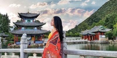 Tour Côn Minh - Đại Lý - Lệ Giang - Shangrila Từ Hà Nội 6n5đ Cô gái khoác khăn họa tiết đỏ đứng bên cầu đá trước lầu Đắc Nguyệt ở hồ Hắc Long Đầm Lệ Giang