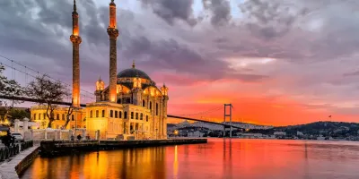 Thánh đường Ortaköy lên đèn bên eo biển Bosphorus và cầu Bosphorus dưới hoàng hôn rực rỡ ở Istanbul