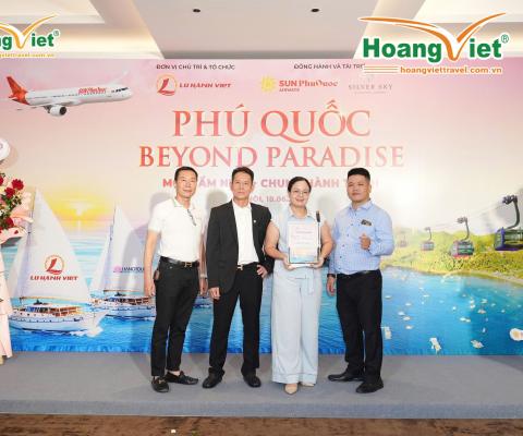 Bốn người đứng mỉm cười trước phông nền "Phú Quốc Beyond Paradise". Không khí hân hoan với hoa và các hình ảnh mang chủ đề du lịch.