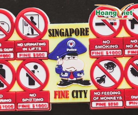 Hình minh họa một viên cảnh sát hoạt hình nghiêm nghị có nhãn "Thành phố Singapore xinh đẹp" xung quanh là các biển báo: Cấm nhai kẹo cao su, tiểu tiện, xả rác, khạc nhổ, hút thuốc, nuôi thú cưng, cho khỉ ăn và cấm ăn sầu riêng, mỗi hành vi đều bị phạt tiền.