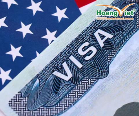Ảnh cận cảnh một thị thực Mỹ che khuất một phần lá cờ Mỹ với những ngôi sao trắng trên nền xanh. Hình ảnh truyền tải chủ đề về du lịch và nhập cư.