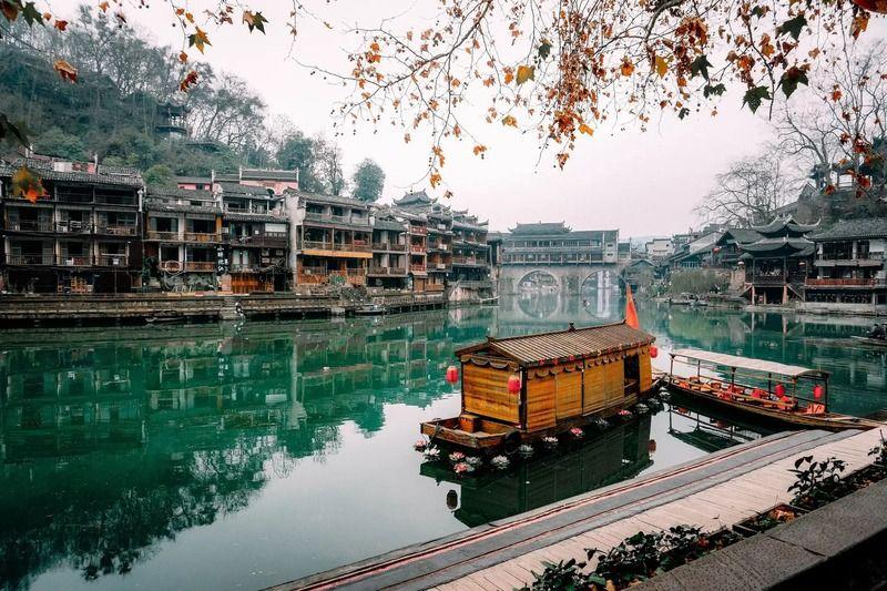 Tour Trương Gia Giới - Phượng Hoàng Cổ Trấn từ Hà Nội Những chiếc thuyền gỗ truyền thống nhẹ nhàng trôi trên dòng sông xanh ngọc êm đềm, hai bên là những công trình kiến trúc cổ kính của Trung Hoa. Lá mùa thu rụng xuống càng làm tăng thêm vẻ thanh bình.