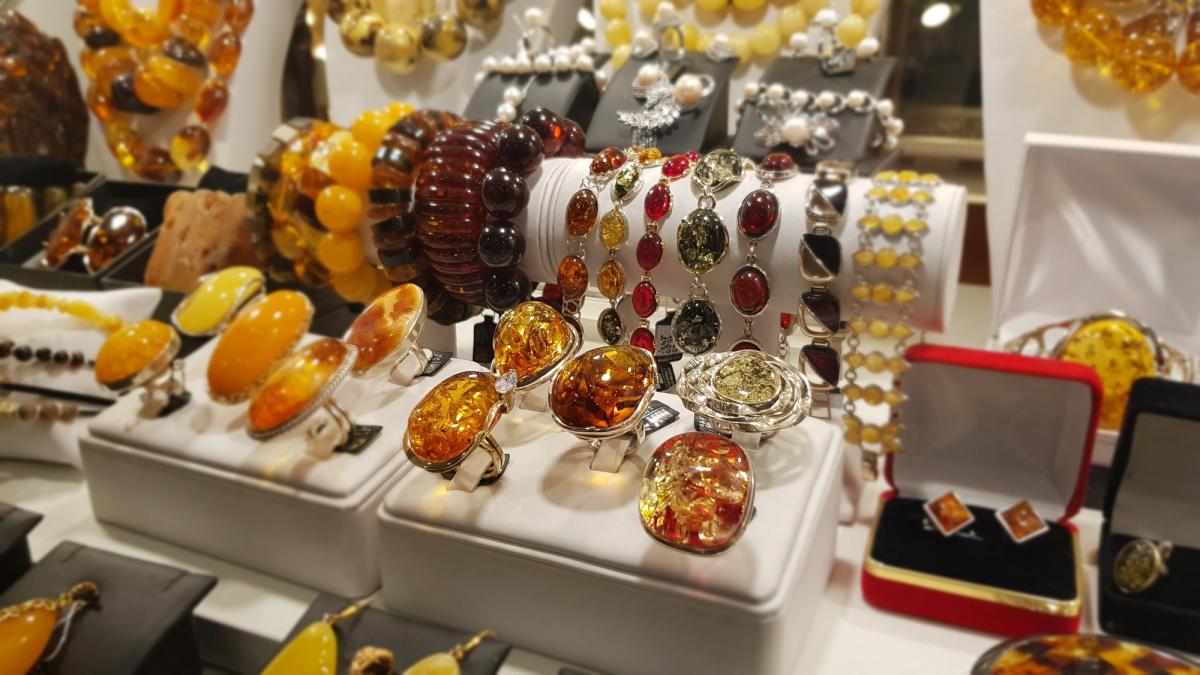 Một màn trưng bày trang sức rực rỡ với nhiều loại nhẫn, vòng tay và bông tai màu hổ phách được đặt trên nền trắng, tạo nên một không gian trang nhã và sang trọng.