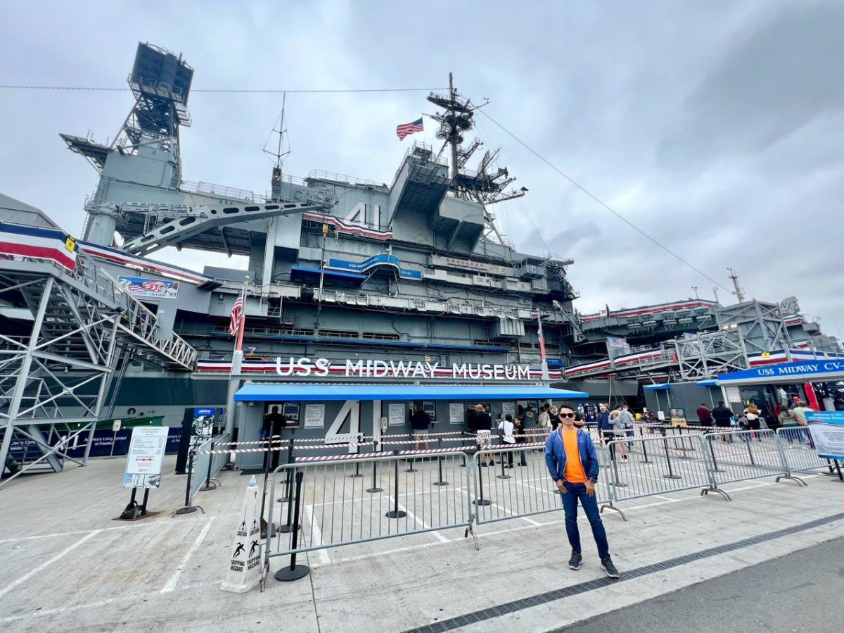 Bảo tàng USS Midway, một tàu sân bay lớn với tháp điều khiển và lá cờ Mỹ nổi bật, đang neo đậu dưới bầu trời trong xanh, gợi lên lịch sử và lòng yêu nước.