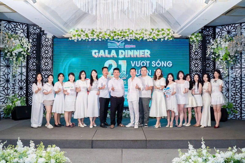 Nhóm nhân viên chi nhánh 141 mặc đồ trắng giơ ngón tay cái chụp ảnh trên sân khấu tiệc Gala Dinner 21 năm