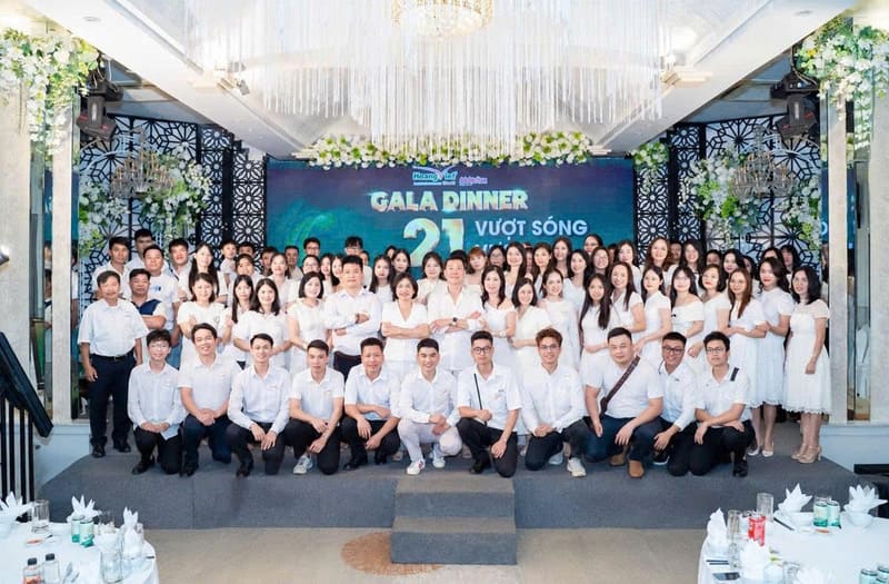 Tập thể nhân viên Hoàng Việt Travel mặc trang phục trắng chụp ảnh kỷ niệm trên sân khấu tiệc Gala Dinner 21 năm