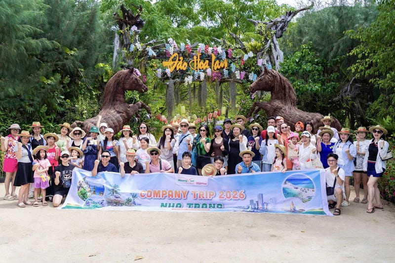 Tập thể Hoàng Việt Travel giơ băng rôn Company Trip 2026 chụp ảnh trước cổng Đảo Hoa Lan Nha Trang