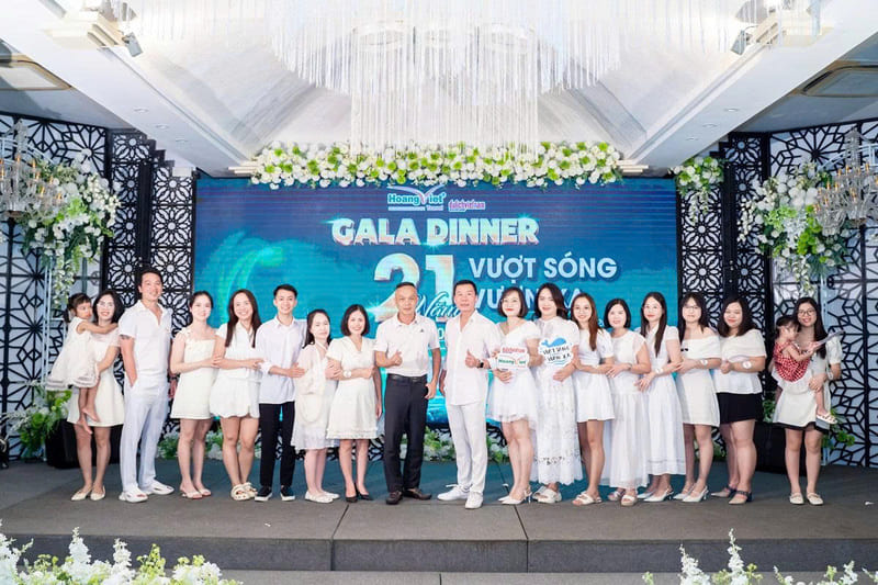 Tập thể văn phòng 93 Hoàng Việt Travel mặc đồ trắng chụp ảnh kỷ niệm trên sân khấu Gala Dinner 21 năm