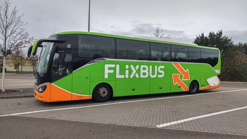 Xe khách FlixBus màu xanh lá cây phối cam đỗ trong bãi xe ngoài trời