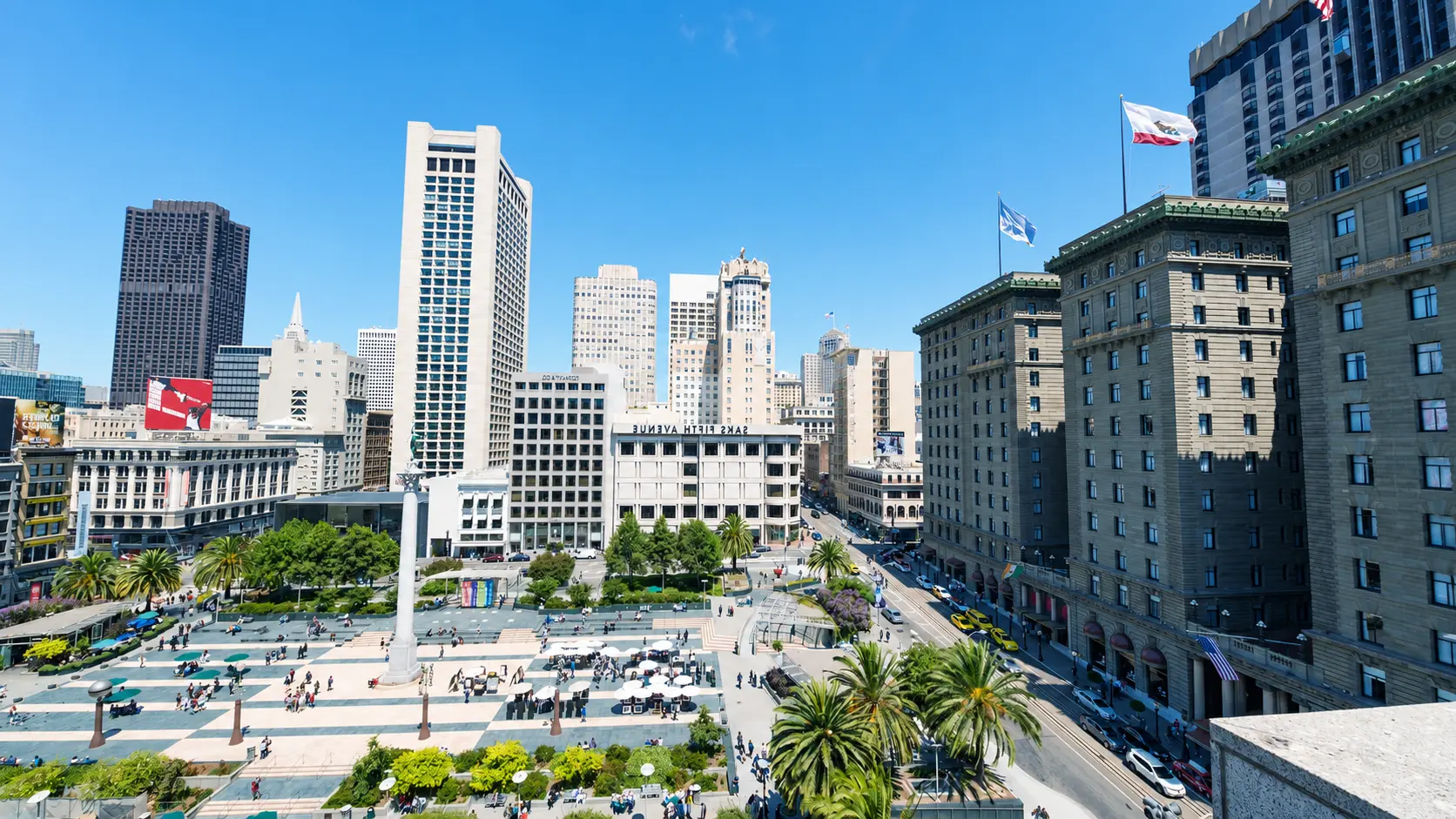 Quảng trường Union Square ở San Francisco với tượng đài trung tâm, hàng cọ xanh và các tòa nhà cao tầng dưới bầu trời trong xanh.