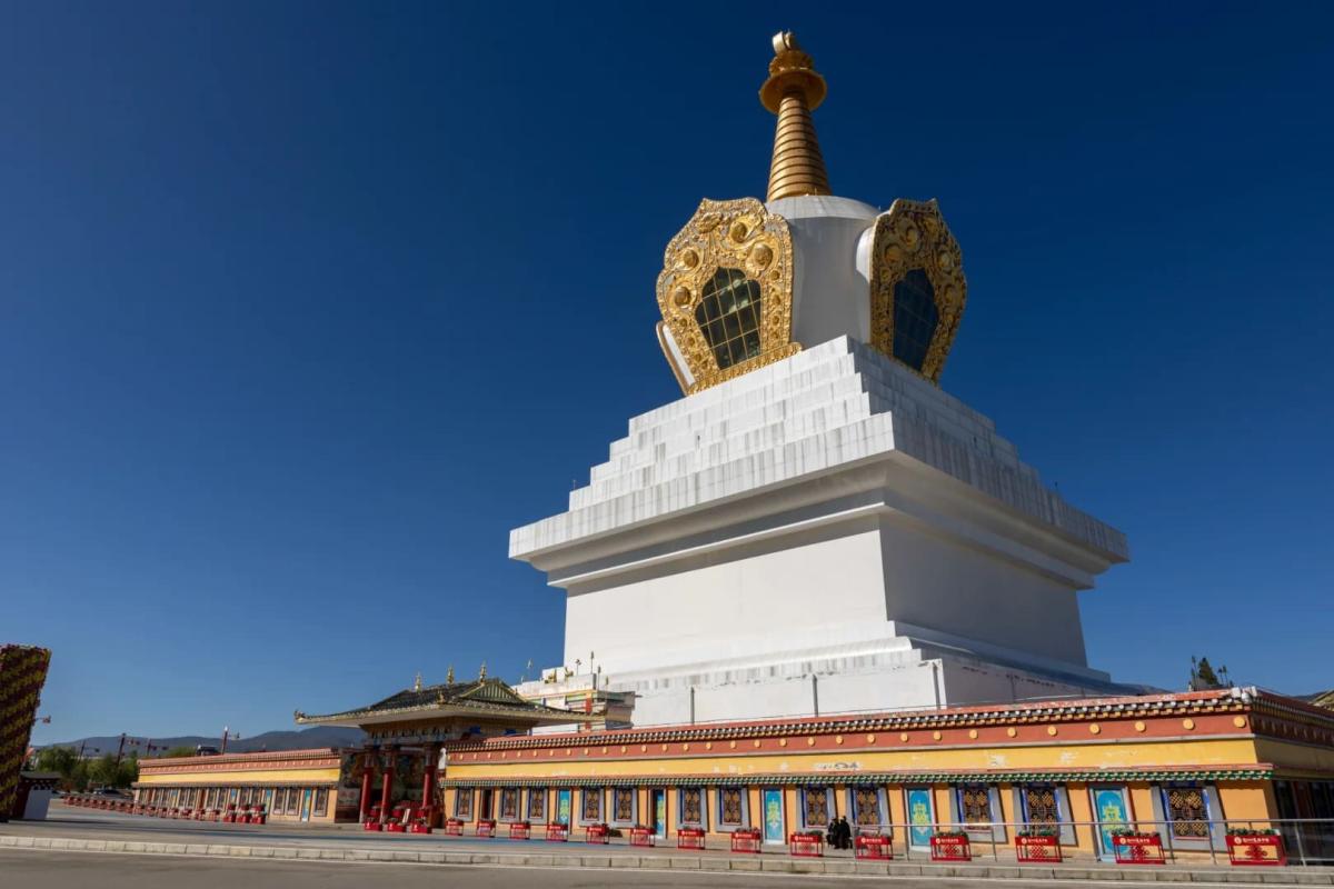 Bảo tháp trắng Tây Tạng với đỉnh dát vàng nổi bật trên nền trời xanh tại Shangrila