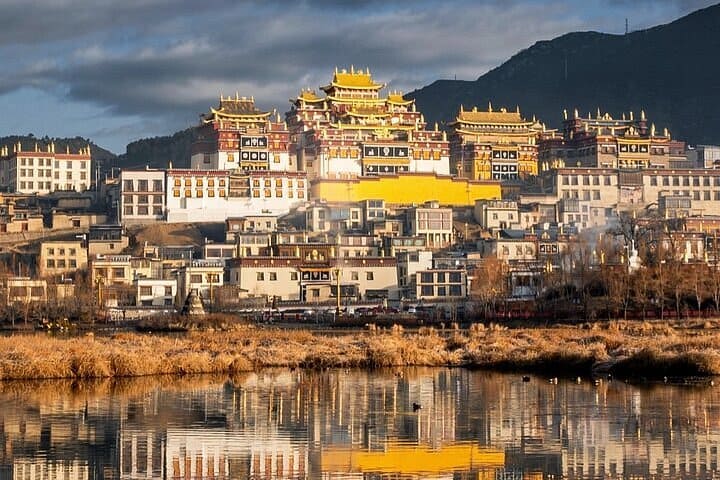 Quần thể tu viện Tùng Tán Lâm mái dát vàng trên sườn núi soi bóng xuống mặt hồ ở Shangrila