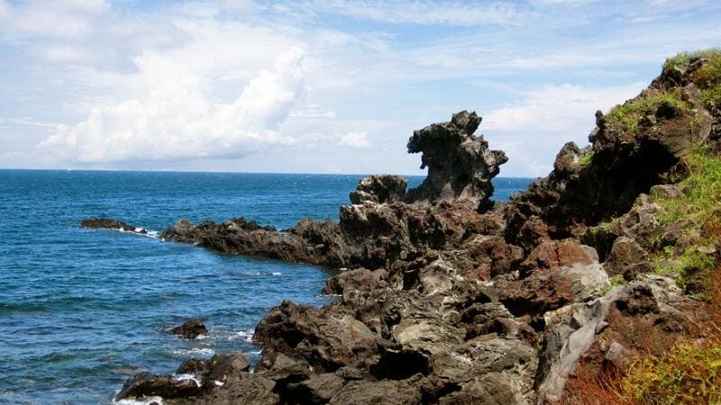 Đá Đầu Rồng Yongduam từ nham thạch đen nhô ra bờ biển xanh tại đảo Jeju