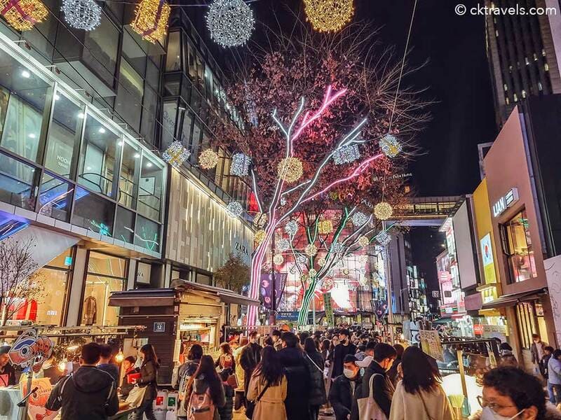 Phố mua sắm Myeongdong Seoul về đêm đông đúc người qua lại bên các quầy hàng đường phố và đèn LED trang trí