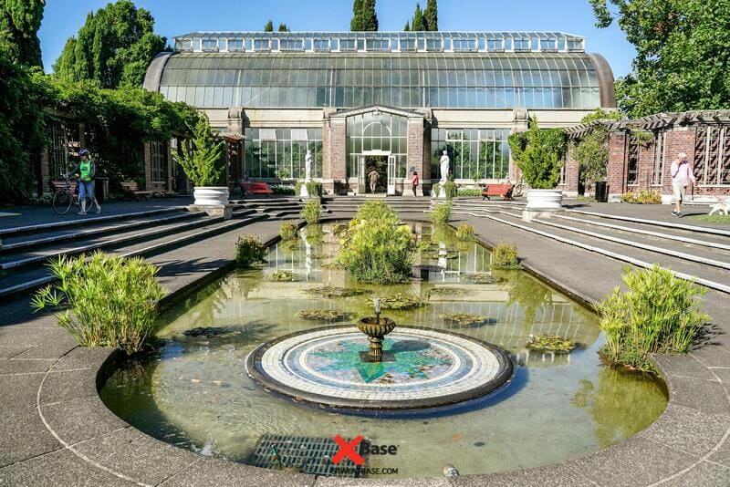 Hồ nước nhỏ có đài phun nước tròn phía trước nhà kính Wintergardens bằng kính và gạch ở Auckland