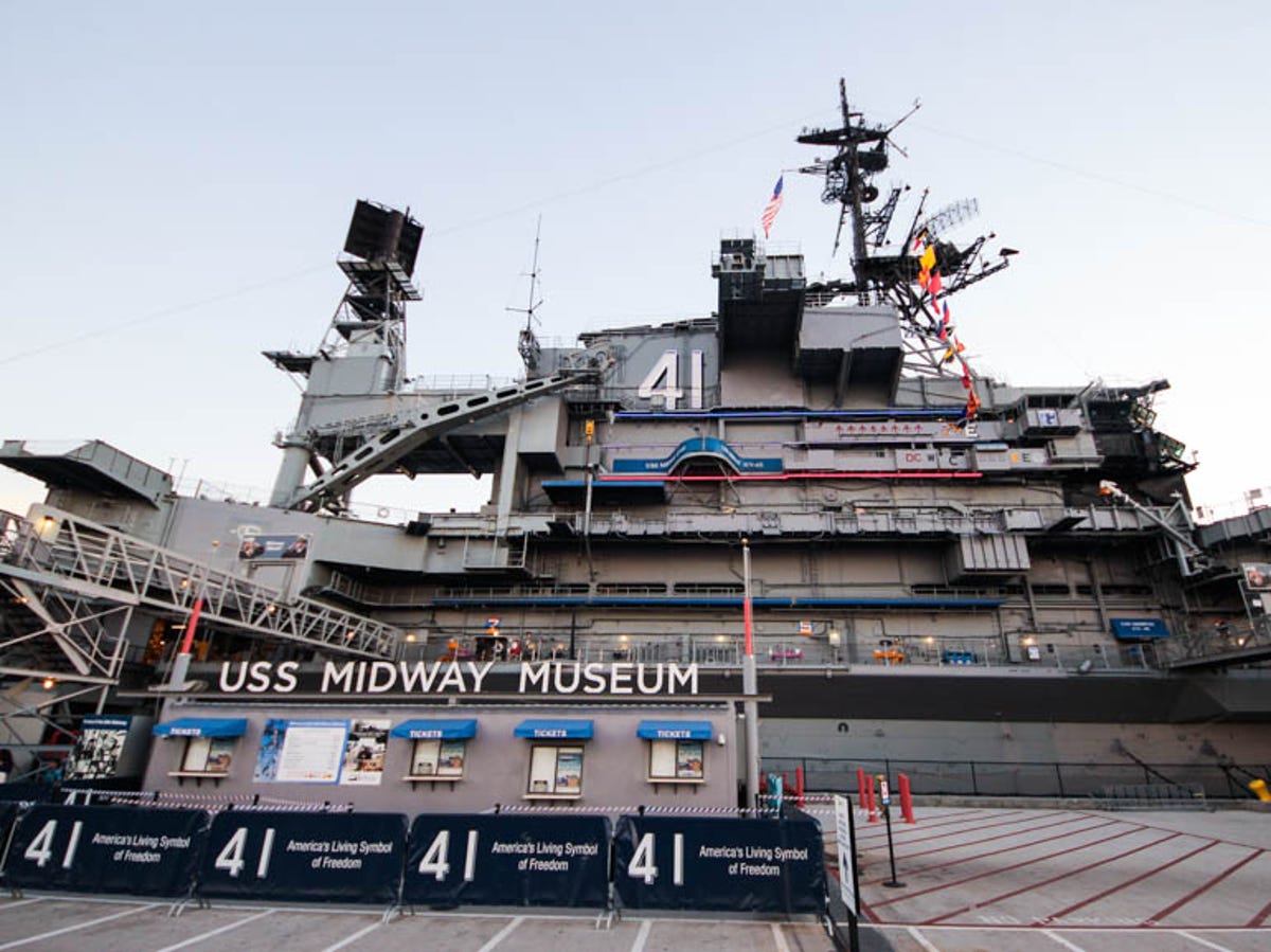 Bảo tàng USS Midway, một tàu sân bay lớn với tháp điều khiển và lá cờ Mỹ nổi bật, đang neo đậu dưới bầu trời trong xanh, gợi lên lịch sử và lòng yêu nước.