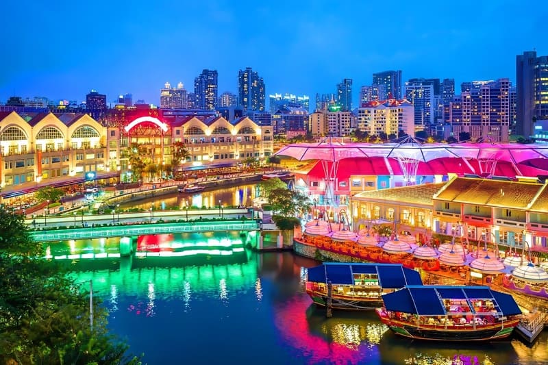 Bờ sông Singapore vào ban đêm, ánh đèn lung linh phản chiếu trên mặt nước, tạo nên khung cảnh thơ mộng.