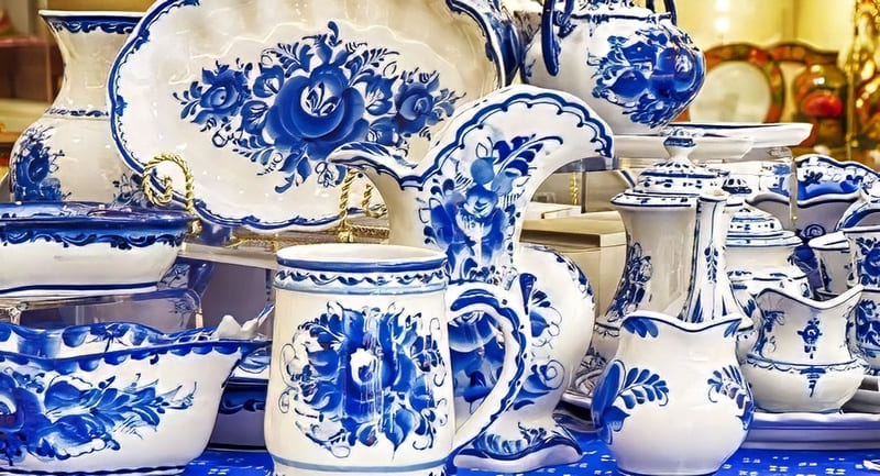 Một bộ sưu tập đồ sứ men lam trắng với những họa tiết hoa văn tinh xảo, bao gồm bình, bát và đĩa. Cách bài trí gợi lên vẻ thanh lịch và sự khéo léo trong chế tác.