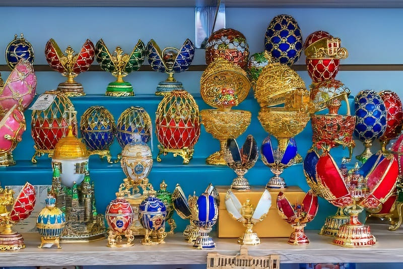 Một bộ sưu tập trứng trang trí sống động, được tô điểm bằng vàng và men màu sắc rực rỡ, được sắp xếp trên các kệ. Bộ sưu tập toát lên vẻ sang trọng và tính nghệ thuật.