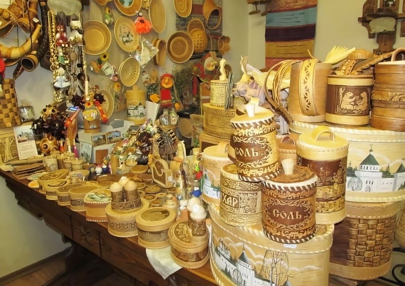 Trên bàn trưng bày nhiều loại hộp và đồ dùng nhà bếp bằng gỗ được chạm khắc tinh xảo. Các vật dụng bao gồm hộp, giỏ và đồ thủ công trang trí.