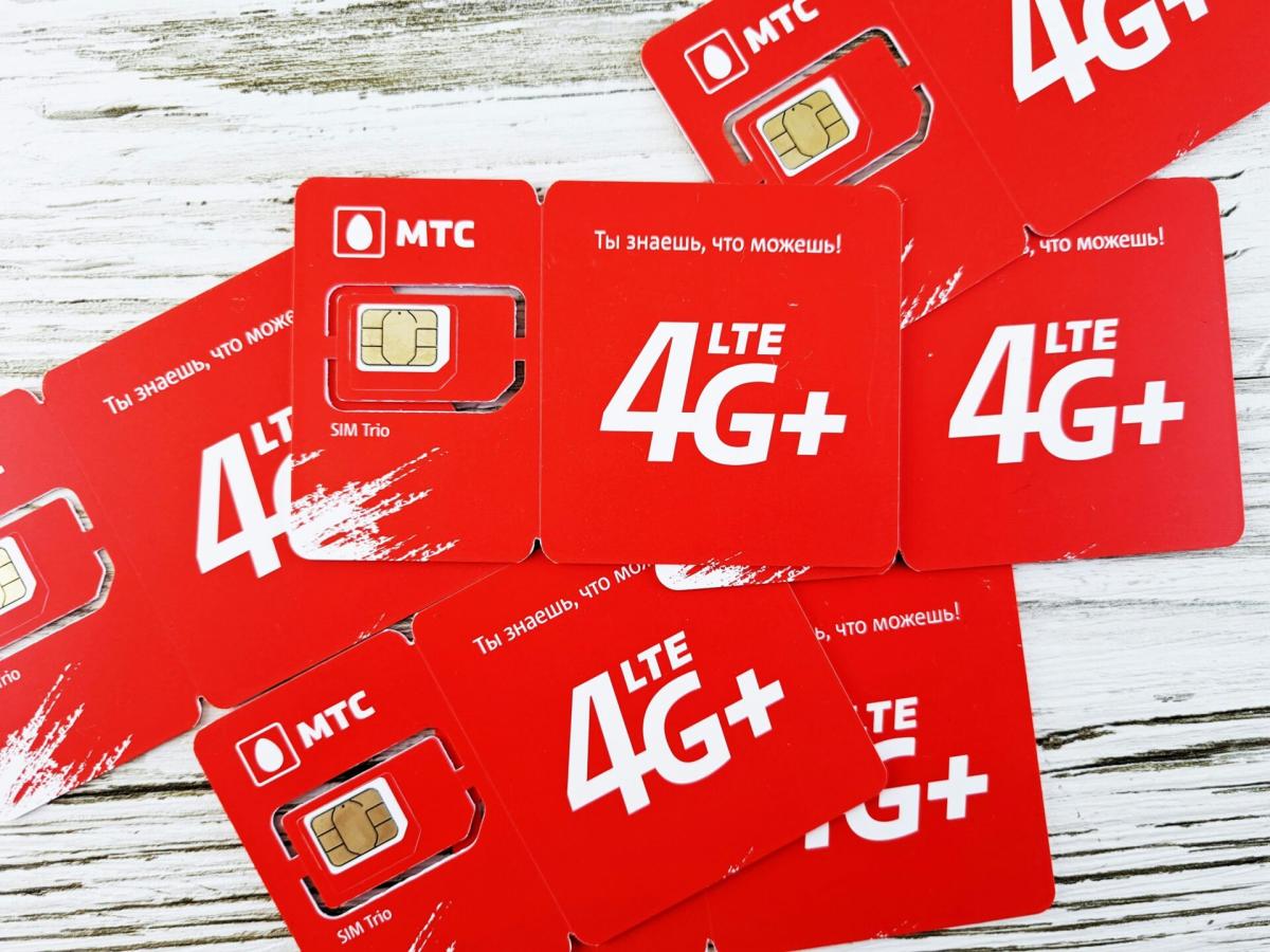 Bao bì thẻ SIM màu đỏ nằm rải rác trên bề mặt gỗ có in logo "4G LTE" và "MTC". Thiết kế bao gồm chữ trắng in đậm và hiệu ứng nét cọ.