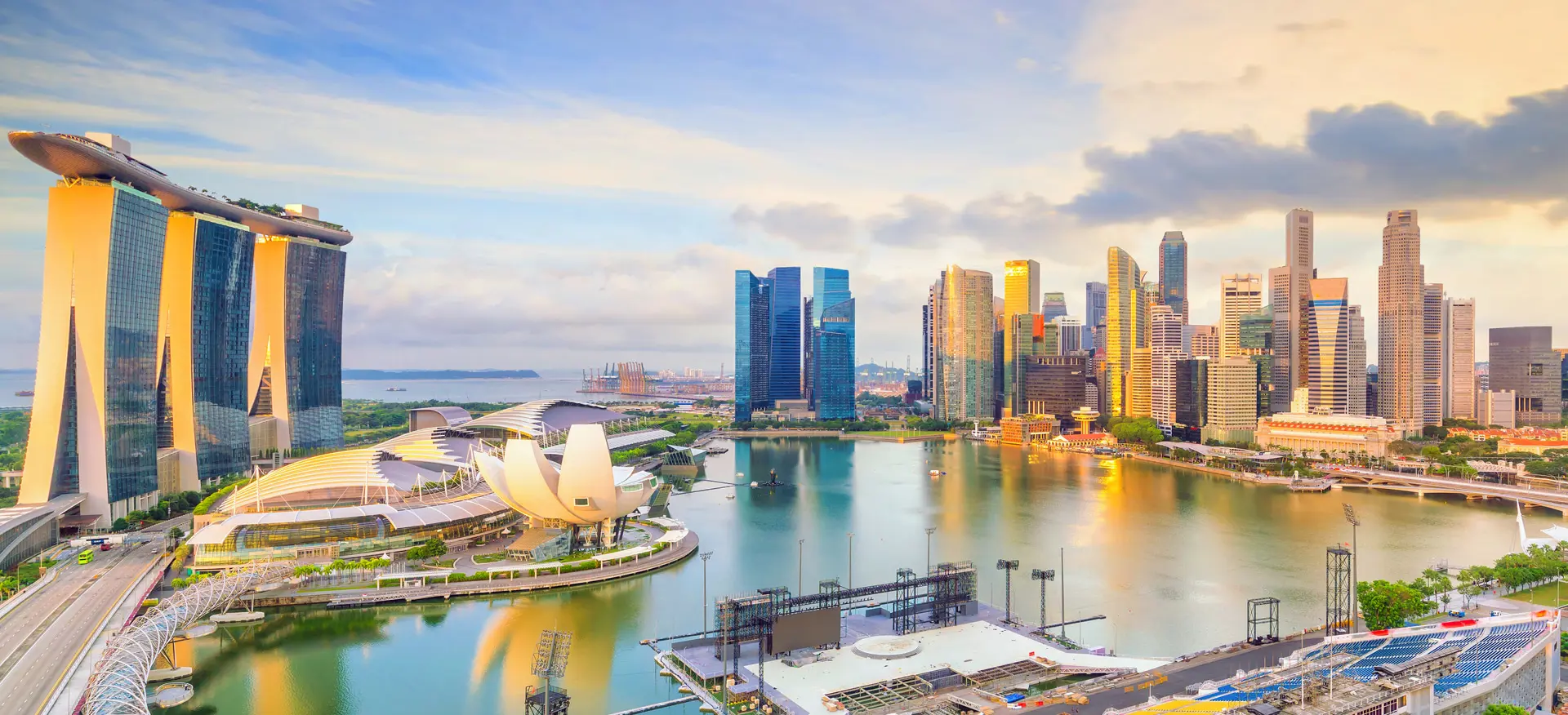 Toàn cảnh đường chân trời Singapore lúc hoàng hôn. Nổi bật là Marina Bay Sands, kiến trúc hiện đại và hình ảnh phản chiếu trên vịnh. Sống động và hiện đại.
