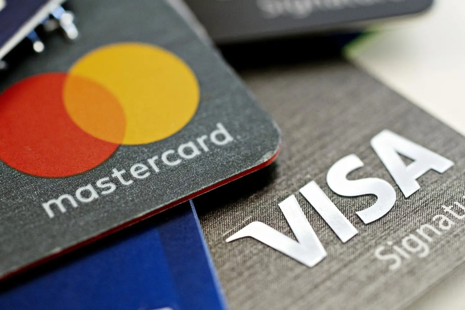 Ảnh cận cảnh hai thẻ tín dụng chồng lên nhau, có logo Mastercard và Visa. Thẻ Mastercard có các vòng tròn màu đỏ và vàng, trong khi thẻ Visa có màu xám với chữ màu trắng.