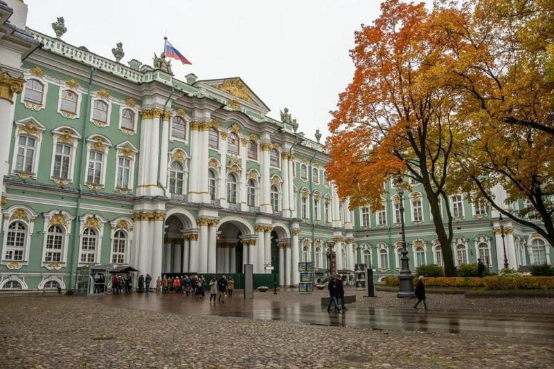 Cung điện màu xanh lá cây nhạt và trắng tráng lệ với những chi tiết trang trí cầu kỳ, quốc kỳ Nga tung bay phía trên. Cây cối mùa thu và quảng trường lát đá ướt tạo nên một bầu không khí thanh bình.